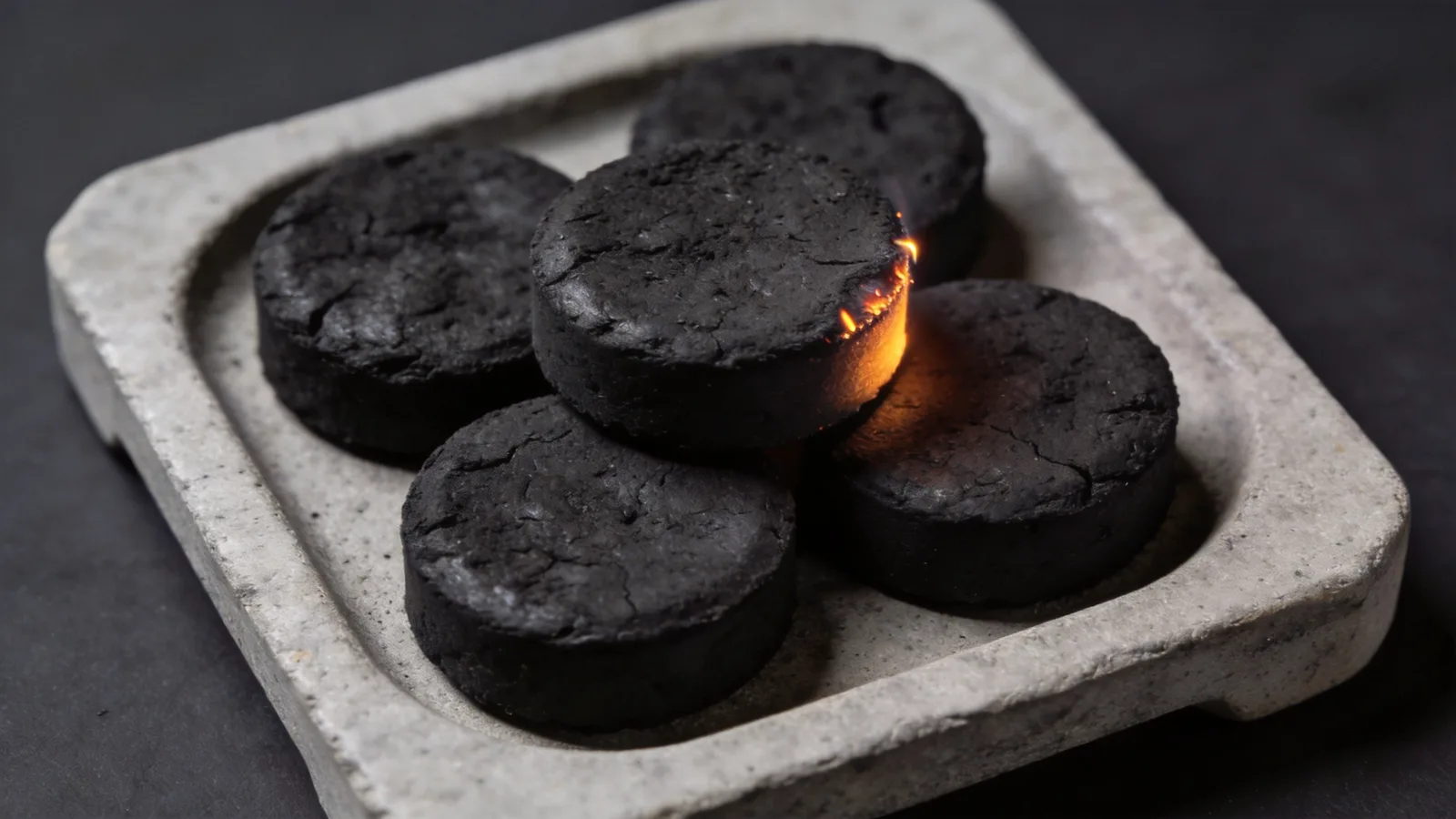 Instant-light charcoal tablets on a stone tray, one lit — conceptual illustration